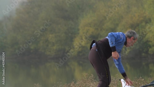 A Senior Man Putting On His Life Vest For Kayaking - Medium Shot photo