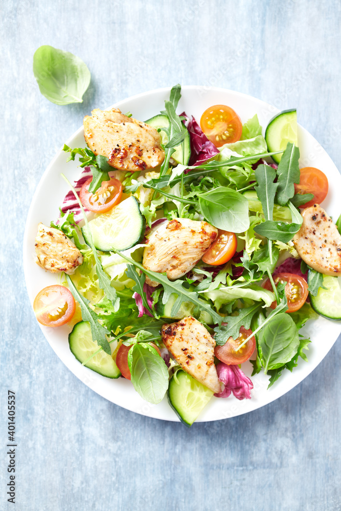 Salad with Chicken Breast, Cherry Tomatoes, Cucumber, Rocket and fresh Basil. Bright wooden background. Top view. Close up. 