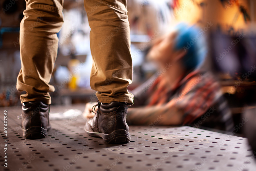 legs in trousers and boots are on the table. legs in trousers and boots are on the table.