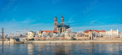 Panoramic view over Magdeburg historical downtown in Winter with icy trees and blue sky at sunny day, Germany.