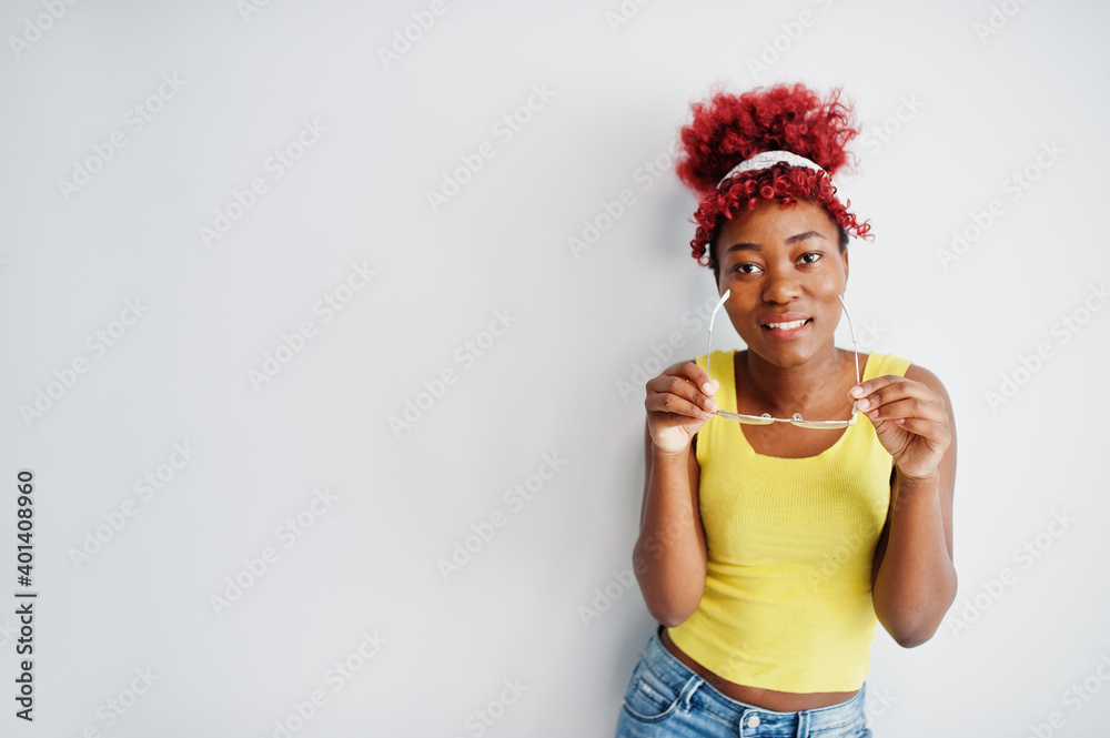 African american woman in yellow singlet and eyglasses against white wall.