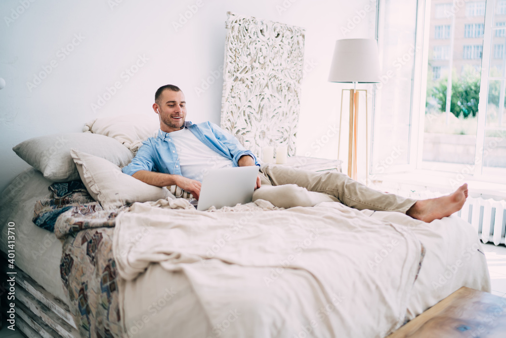 Positive young man relaxing in cozy bedroom Positive young man relaxing in cozy bedroom