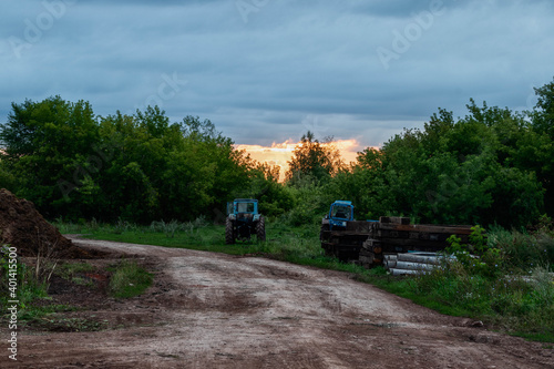 Agricultural equipment stands near the road in the evening.