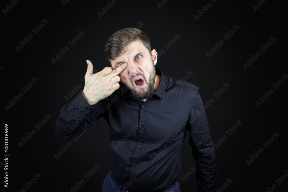 a man in a black shirt and on a black background shows his middle fingers makes obscene gestures a man in a black shirt and on a black background shows his middle fingers makes obscene gestures