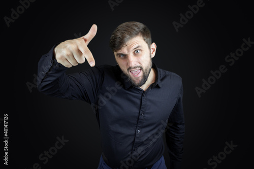 a man in a black shirt and on a black background points his index finger down © Roman