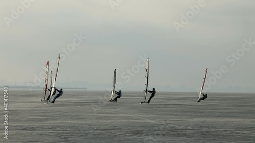 group of extreme athletes windboarders, glide under sail on the frozen sea ice photo