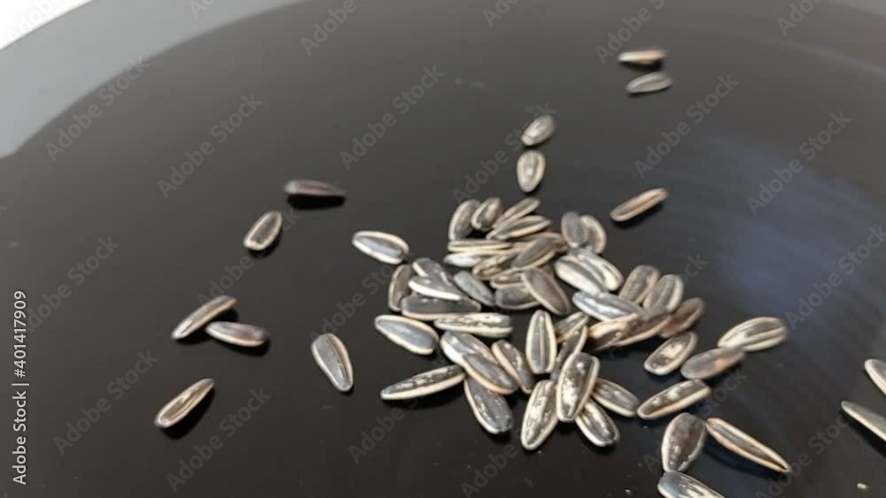 pouring sunflower seeds into a black bowl