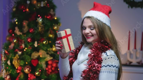 Portrait of beautiful happy woman with blond hair in winter sweater. Cheerful girl holding New Year's gift in her hands.