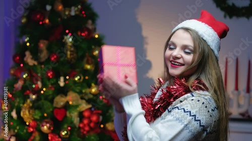Portrait of beautiful happy woman with blond hair in winter sweater. Cheerful girl holding New Year's gift in her hands.