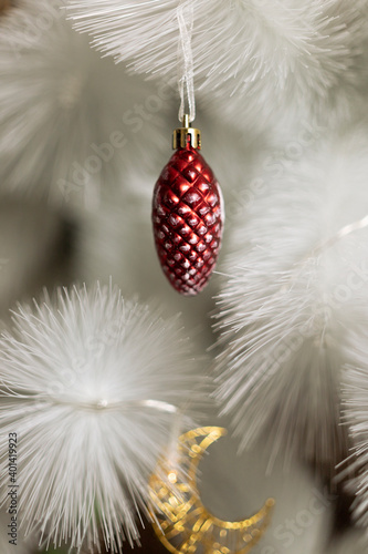toys on a white christmas tree red pine cone and golden crescent