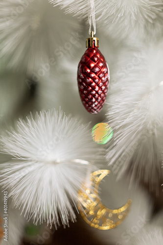 toys on a white christmas tree red pine cone and golden crescent
