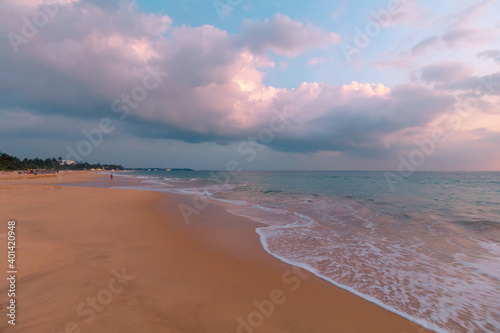 Fototapeta Naklejka Na Ścianę i Meble -  Beautiful ocean beach at sunset. Foamy waves over wheat sand and a beautiful cloudy sky.