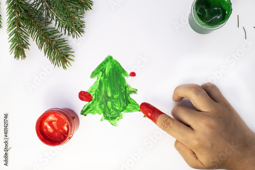 the hand of a little boy who draws a Christmas tree with his finger.