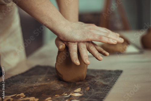 A man wrinkles clay with his hands. Work on the pottery wheel. The master is preparing clay.