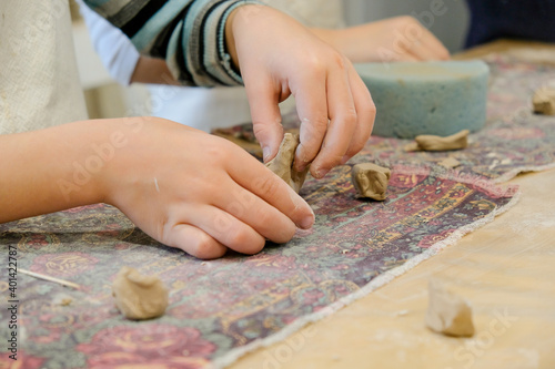A child molds a product from clay in a modeling lesson.