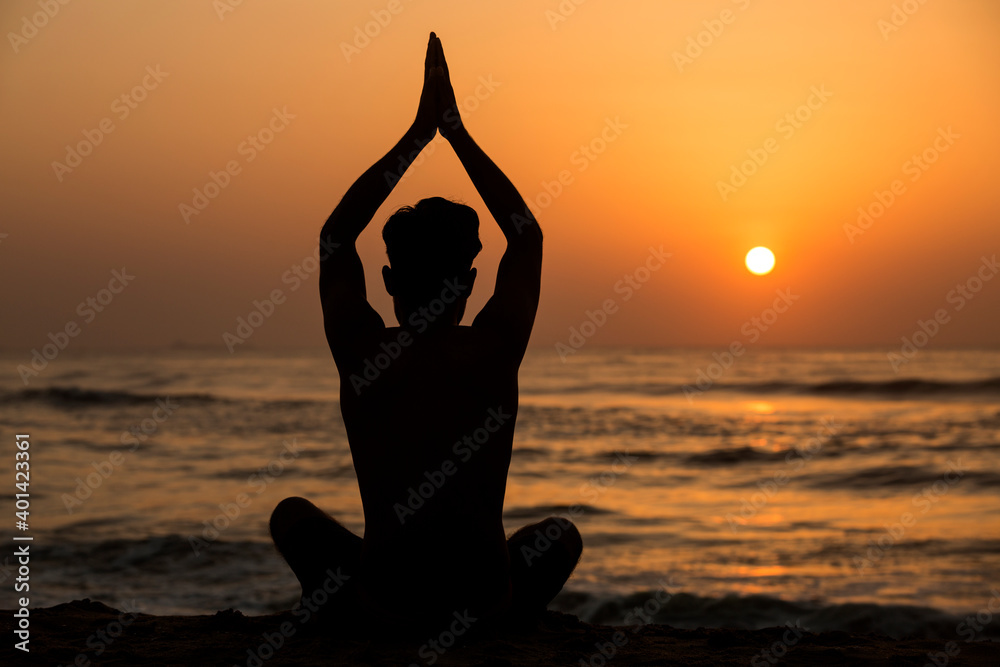 silhouette of person meditating on beach