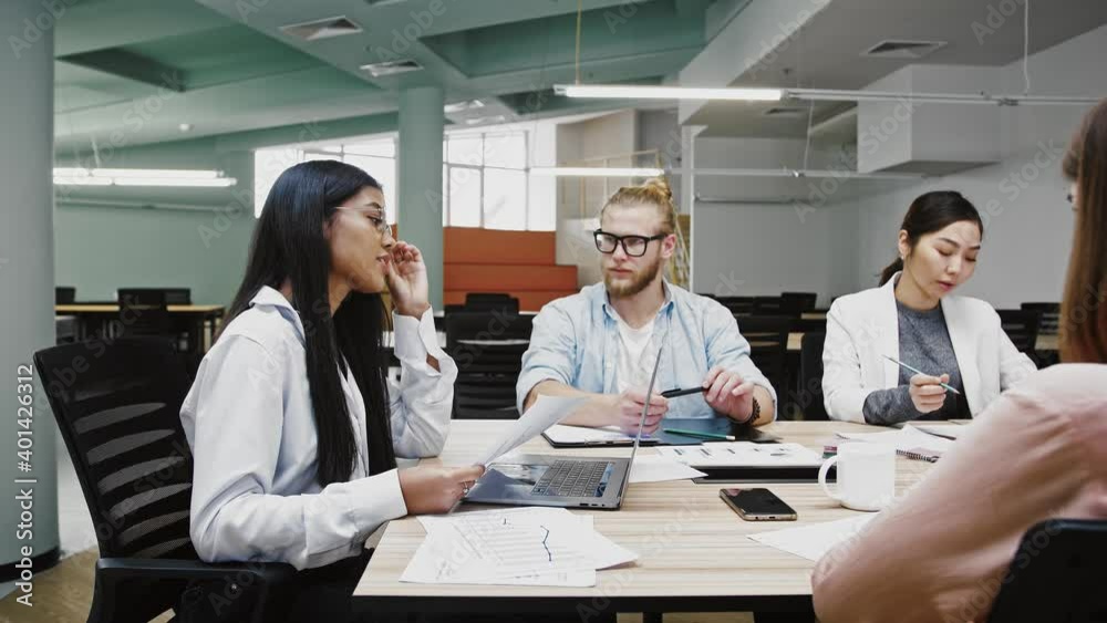 Businesswoman boss conveying ideas concerning to startup project to group of diverse colleagues, sitting at table in office Businesswoman boss conveying ideas concerning to startup project to group of diverse colleagues, sitting at table in office