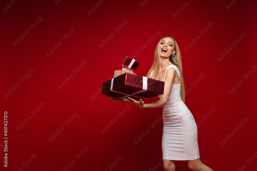 cheerful caucasian young female model in white dress with a lot of gifts, picture isolated on red background cheerful caucasian young female model in white dress with a lot of gifts, picture isolated on red background