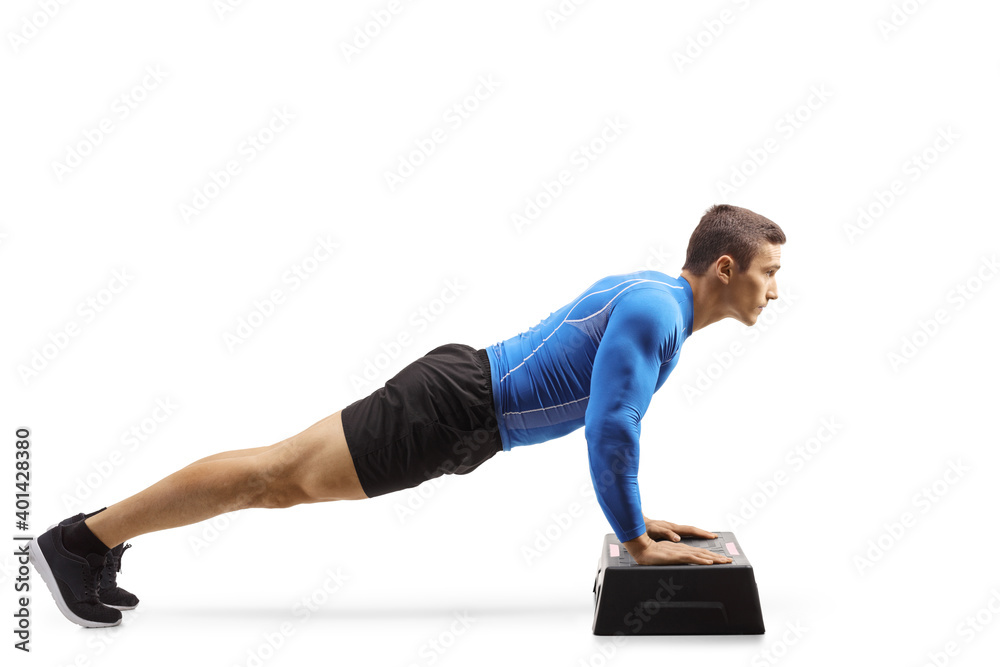 Muscular man exercising push-ups on a step aerobic platform