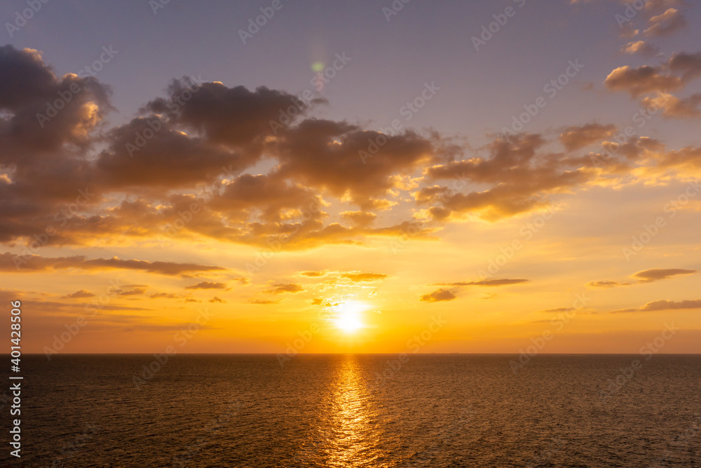 Sunset reflection ocean. beautiful sunset behind the clouds and blue sky above the over ocean landscape background