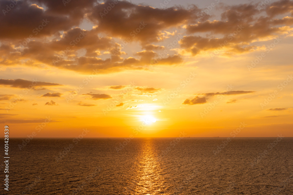 Sunset reflection ocean. beautiful sunset behind the clouds and blue sky above the over ocean landscape background