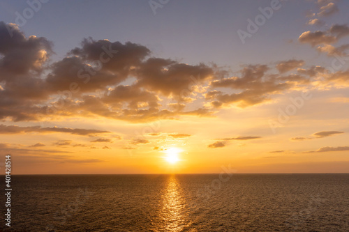 Sunset reflection ocean. beautiful sunset behind the clouds and blue sky above the over ocean landscape background © Achira22
