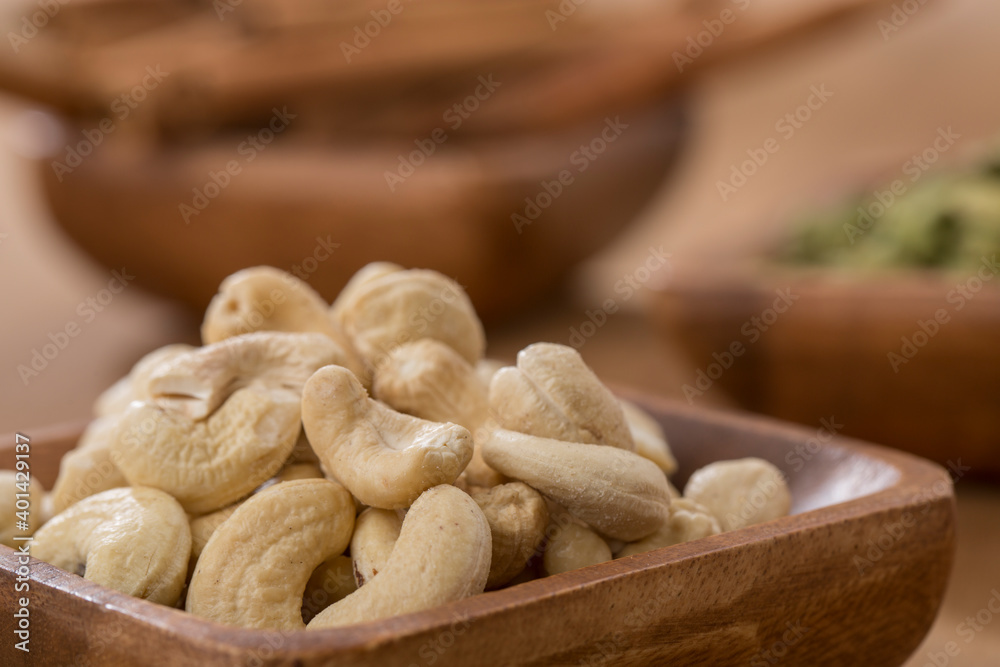 wooden bowl of cardamom, cinnamon and cashew on wooden table. wooden bowl of cardamom, cinnamon and cashew on wooden table.