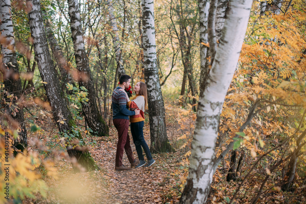 A romantic date, a walk in nature. Young couple of lovers together in the forest in early autumn.