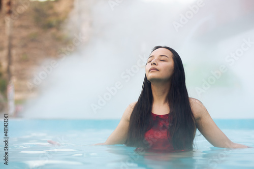 Young woman swimming in thermal waters pool
