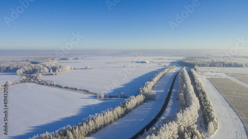 Winter road along the fields between cities aerial view from a drone. Winter road view from a drone