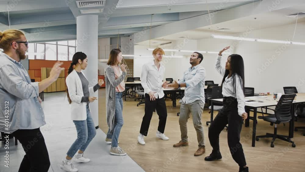 Young team of multiracial diverse colleagues are smiling and dancing rejoicing about the signed business contract Young team of multiracial diverse colleagues are smiling and dancing rejoicing about the signed business contract