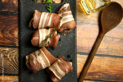 Fresh, raw, uncooked pork rolls with wooden spoon on a table. Cooking background.