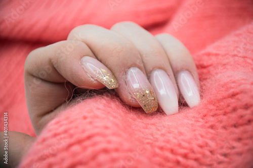 Closeup of hand of woman with beautiful nails in pink pullover background