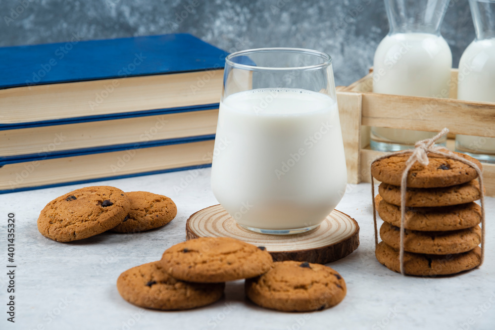 A glass cup of tasty milk with cookies and books A glass cup of tasty milk with cookies and books