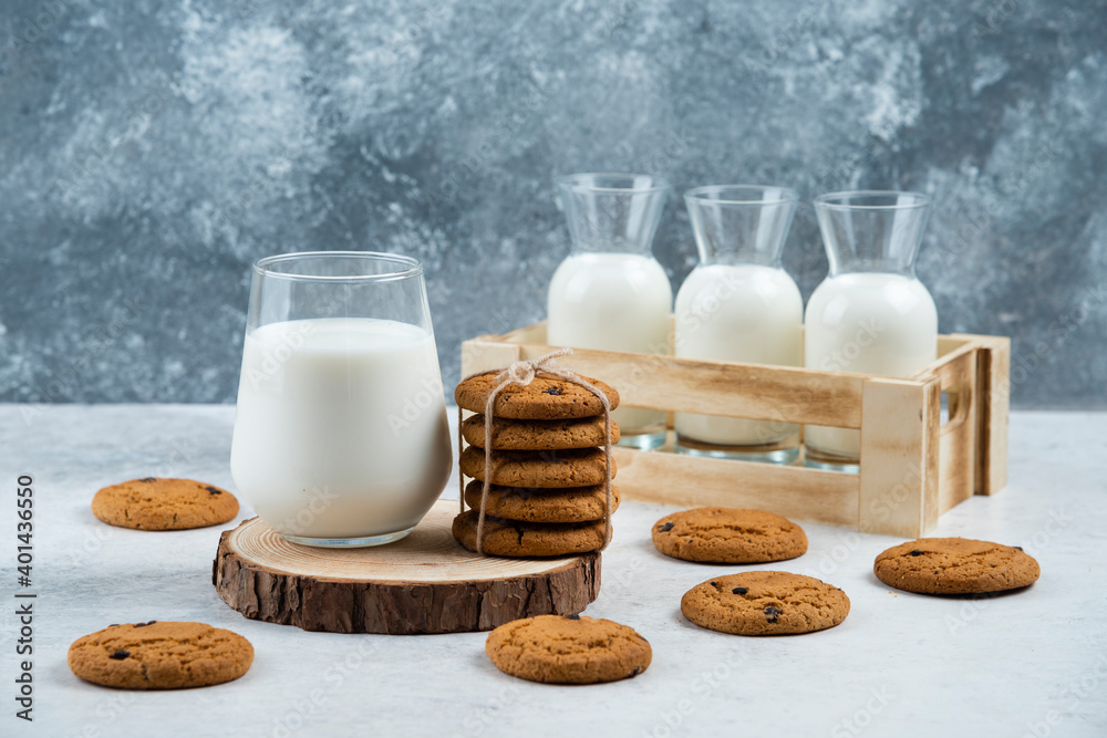 A glass cup of milk with chocolate cookie on a wooden board A glass cup of milk with chocolate cookie on a wooden board