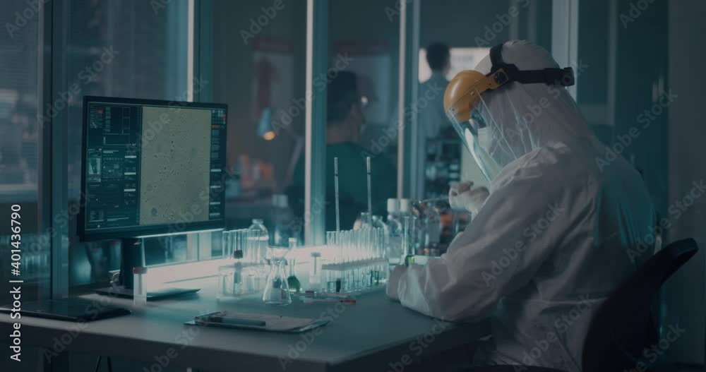 Doctor in protective suit researching vaccine in lab Doctor in protective suit researching vaccine in lab