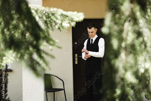 the groom's fees at home. young man is going to the wedding dressing formal clothes. the guy stands near the entrance to the house