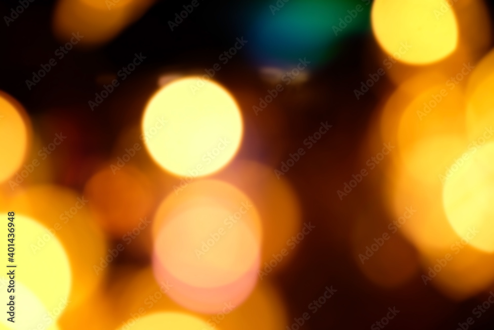 Fototapeta premium Blurred Christmas background, abstraction. orange and yellow glare garlands on a black background..