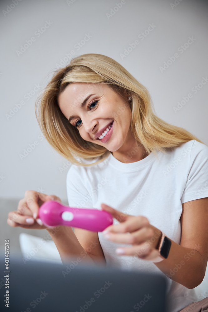 Happy smiling female with smart watch demonstrating modern device for skin care at home Happy smiling female with smart watch demonstrating modern device for skin care at home