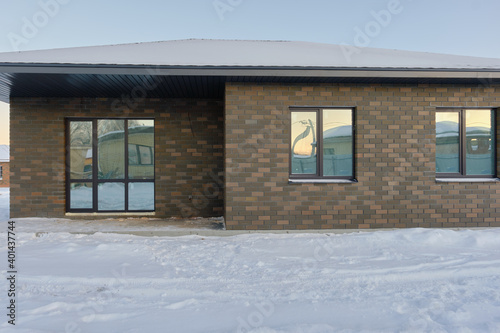 One-story brick house on the background of a snowy winter evening. Construction of low-rise buildings for further sale. Concept of building business. © Мaksim G