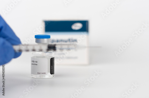 Human fingers in gloves, syringe and Covid-19 vaccine vial photo