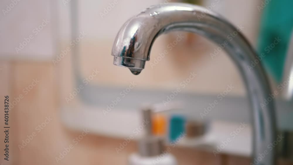 Drops of Water Slowly Flow Down, Fall into Sink from Water Tap. Leak.