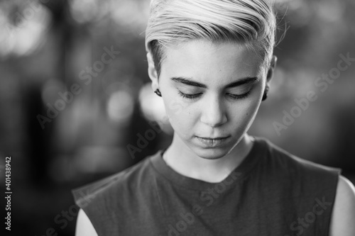 Young woman beauty Tomboy lifestyle with blonde short hair posing in casual clothes in a park in Spain. Jeans and t-shirt showing armes, gender education and non binary teen.