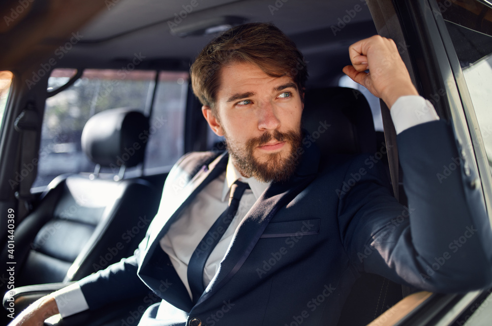 successful rich man in a suit talking on the phone while driving a passenger car
