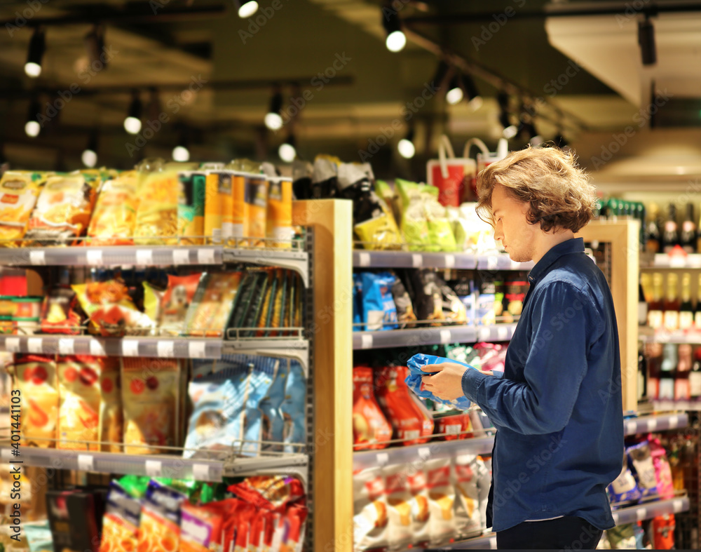 Teenager shopping in supermarket, reading product information