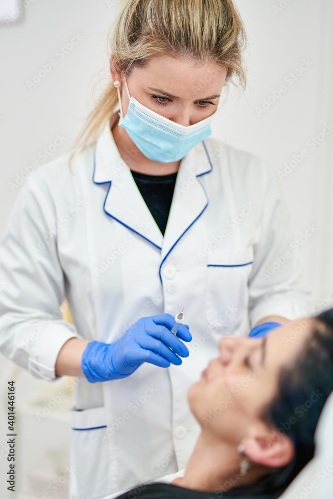 Close up of hands of cosmetologist making botox injection. She is holding syringe. Woman is receiving procedure with enjoyment. High quality photo Close up of hands of cosmetologist making botox injection. She is holding syringe. Woman is receiving procedure with enjoyment. High quality photo
