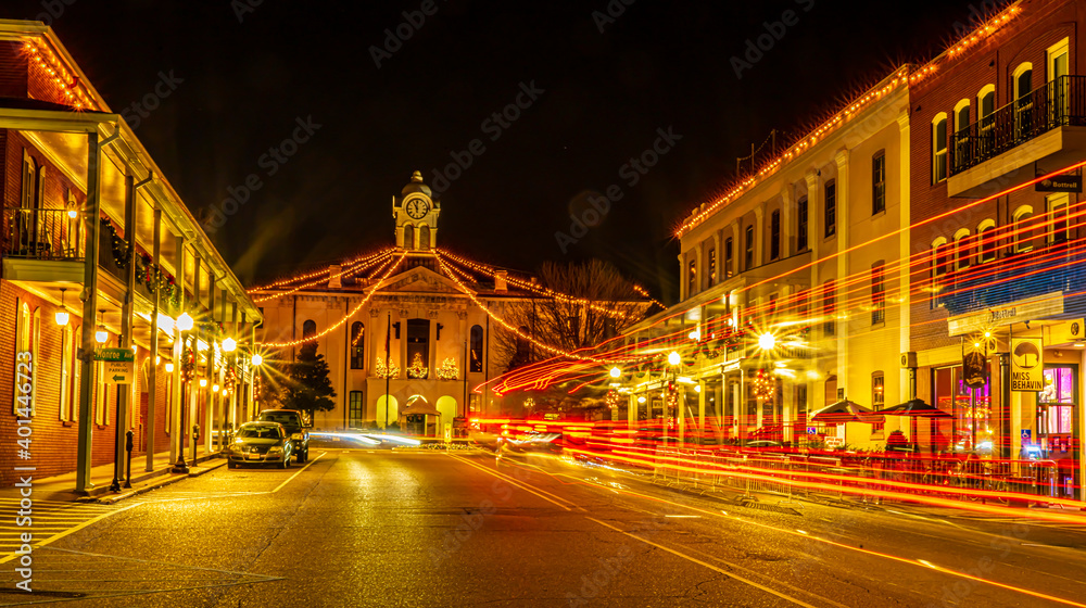 Historic Oxford Courthouse in the middle of town square with streaming head and tail lights at night. Christmas lights dominate.