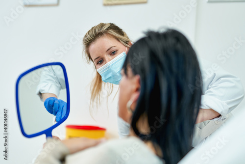 Beautician shows the girl the result of skin care. Woman looking in the mirror after face cleaning.