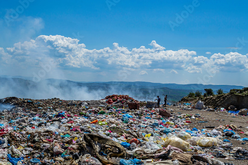 View of garbage field in trash dump or open landfill, food and plastic waste products polluting in a trash dump, Workers hands sorting garbage for recycling.