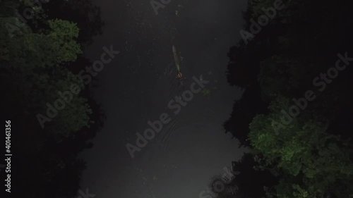 Aerial view of an indigenous person paddling a canoe in a rainforest river photo